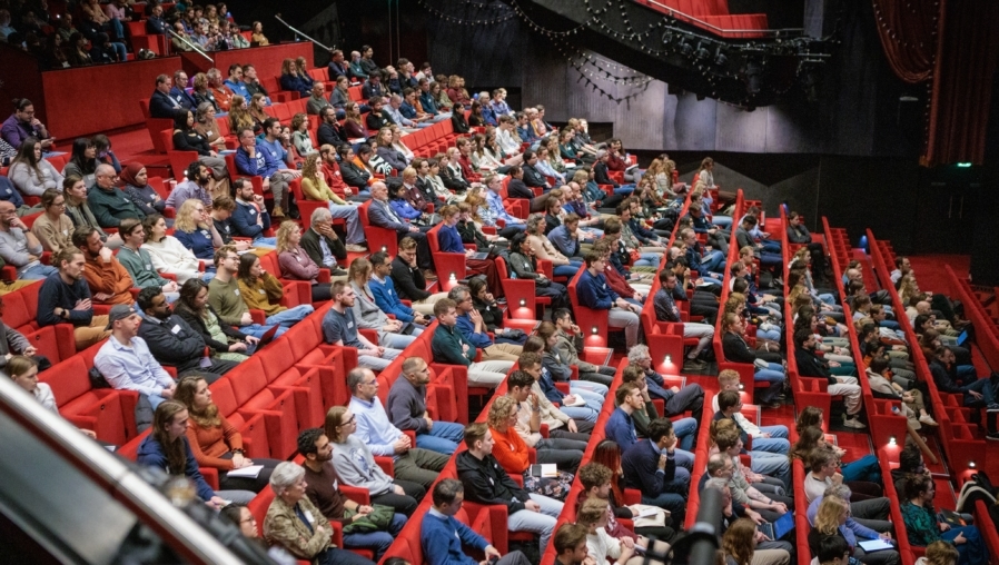mensen zittend in een omhooglopende collegezaal
