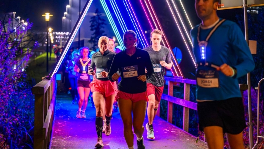 hardlopers rennen in het donker door verlichte bogen